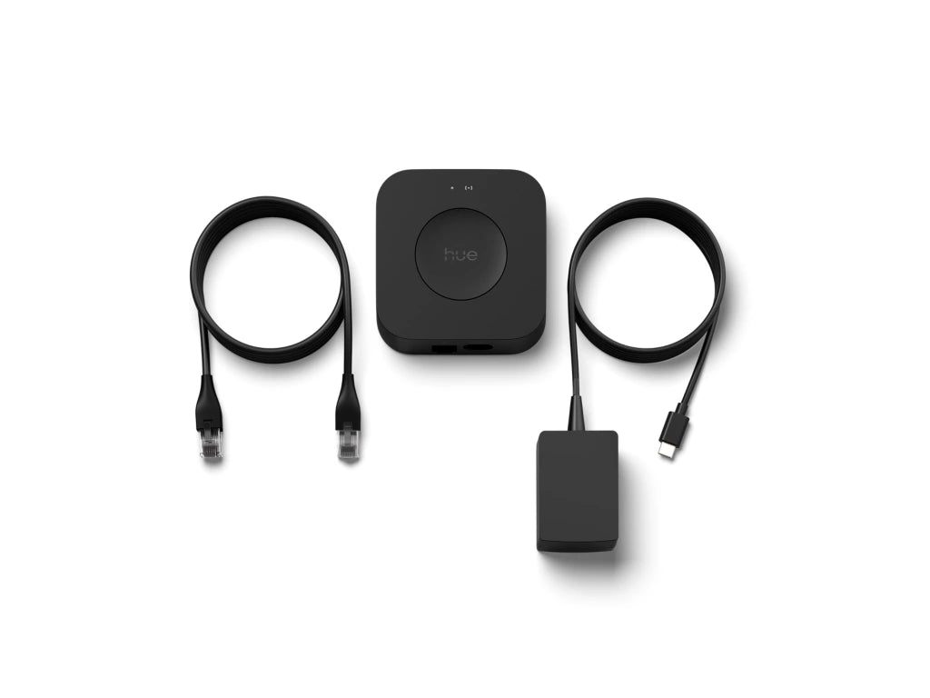 Philips Hue Bridge Pro, musta keskusyksikkö, mukana kaapelit ja virtalähde, älyvalaistuksen ohjaus.
