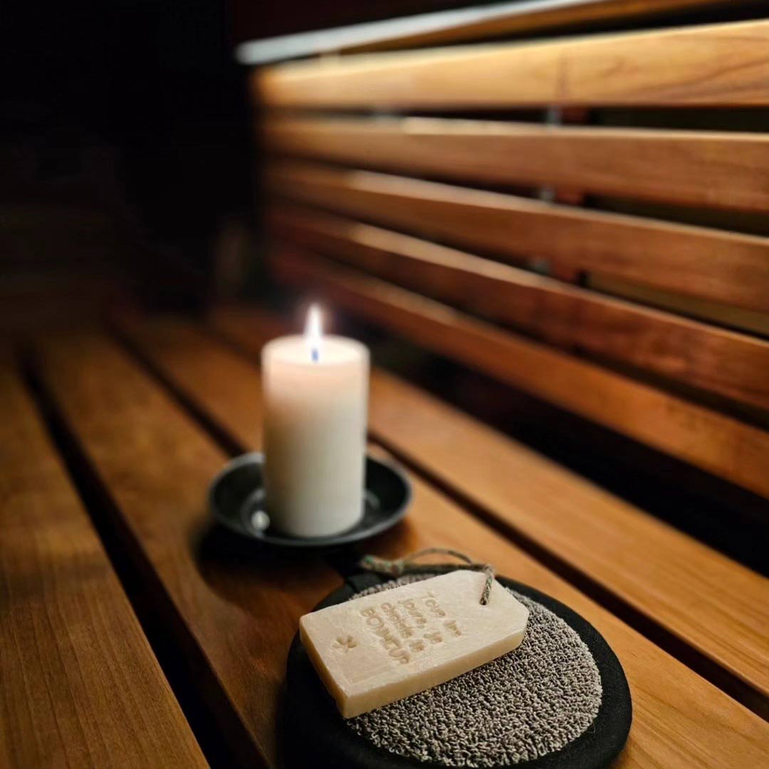 Pisteetön sauna LED-valonauha valaisee tunnelmallisesti saunan, jossa kynttilä ja saippua koristeena.